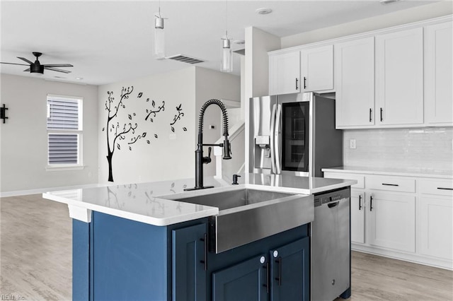 kitchen featuring stainless steel appliances, a sink, visible vents, blue cabinetry, and a center island with sink