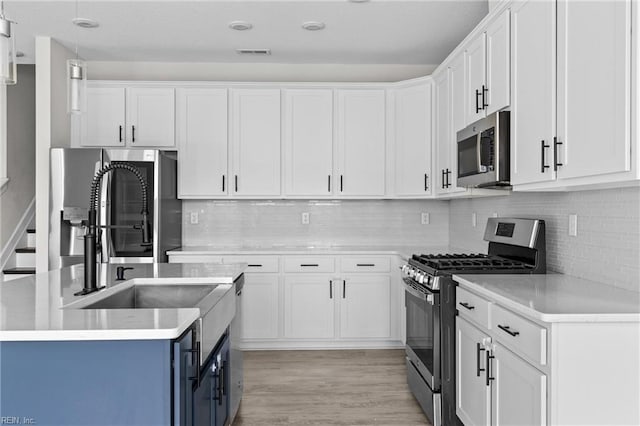 kitchen with stainless steel appliances, light countertops, and white cabinets