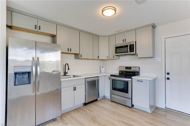 kitchen featuring light wood-type flooring, stainless steel appliances, a sink, and light countertops