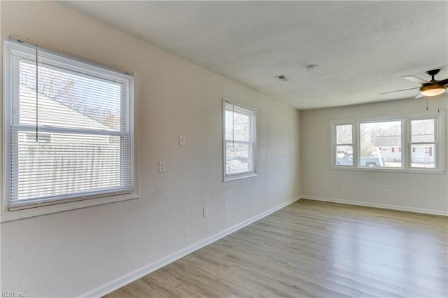 spare room featuring light wood-type flooring, baseboards, and a wealth of natural light