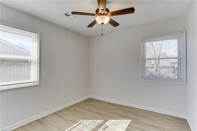 spare room with a ceiling fan, light wood-type flooring, visible vents, and baseboards