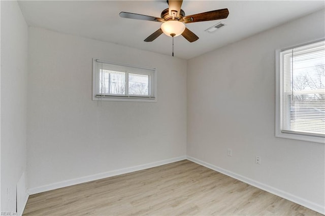 spare room with light wood-style floors, a wealth of natural light, visible vents, and baseboards