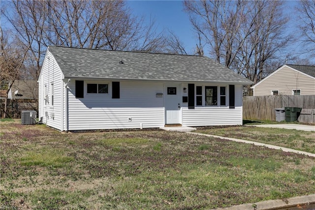 bungalow-style home featuring fence, a front lawn, cooling unit, and roof with shingles