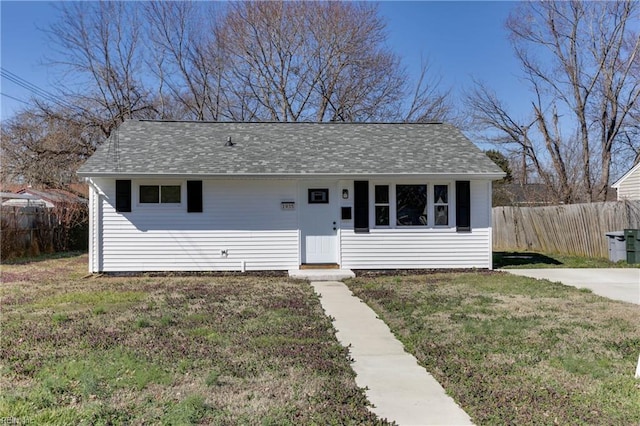 view of front of home with a shingled roof, fence, and a front lawn