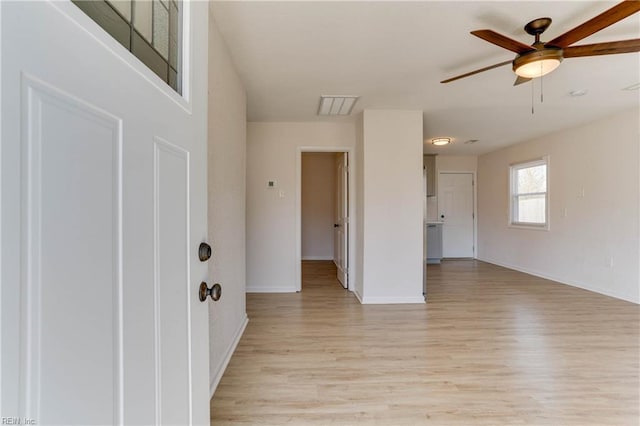 spare room featuring visible vents, light wood finished floors, a ceiling fan, and baseboards