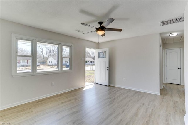 empty room featuring attic access, visible vents, baseboards, a ceiling fan, and light wood-style floors