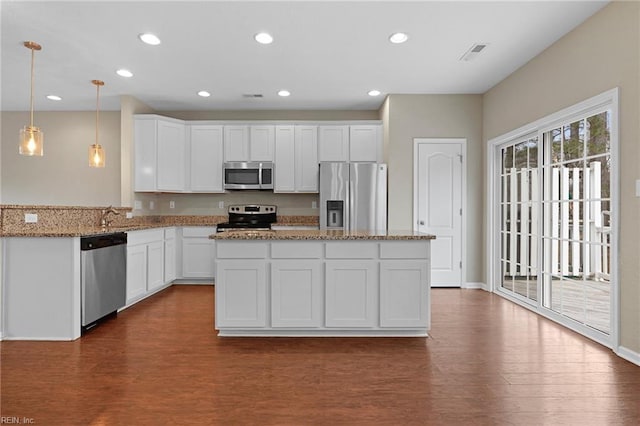 kitchen featuring stainless steel appliances, hanging light fixtures, dark wood-type flooring, white cabinetry, and light stone countertops