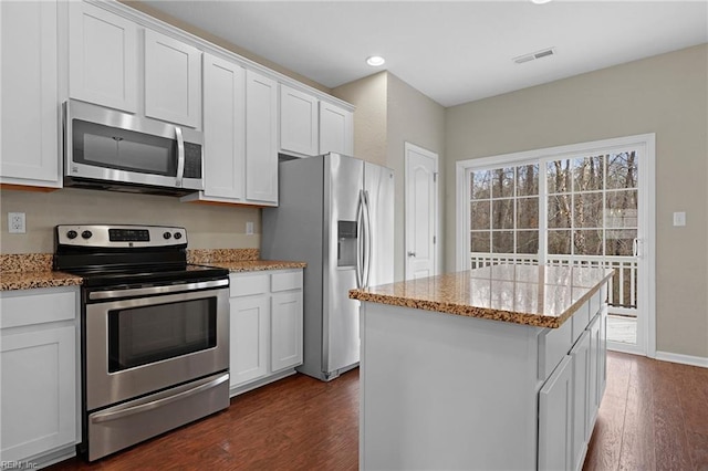 kitchen featuring visible vents, white cabinets, light stone counters, a center island, and stainless steel appliances