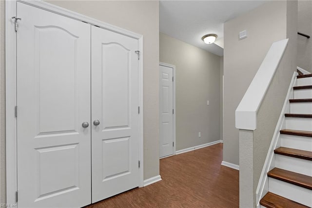 hallway with stairs, wood finished floors, and baseboards