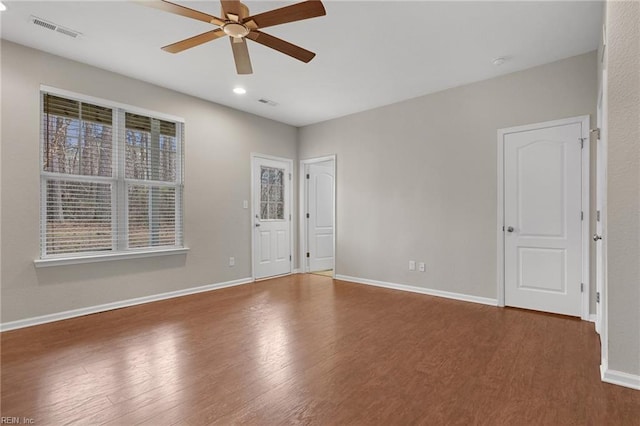 spare room featuring a ceiling fan, baseboards, visible vents, and wood finished floors