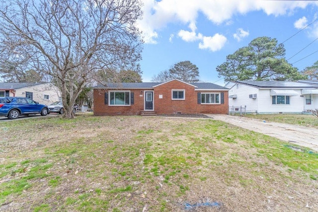 single story home with crawl space, a wall mounted AC, a front lawn, and brick siding