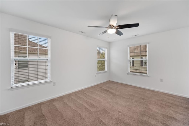 carpeted empty room featuring baseboards, visible vents, and a ceiling fan