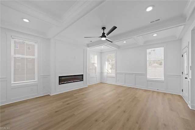 unfurnished living room with coffered ceiling, a decorative wall, beamed ceiling, and a glass covered fireplace