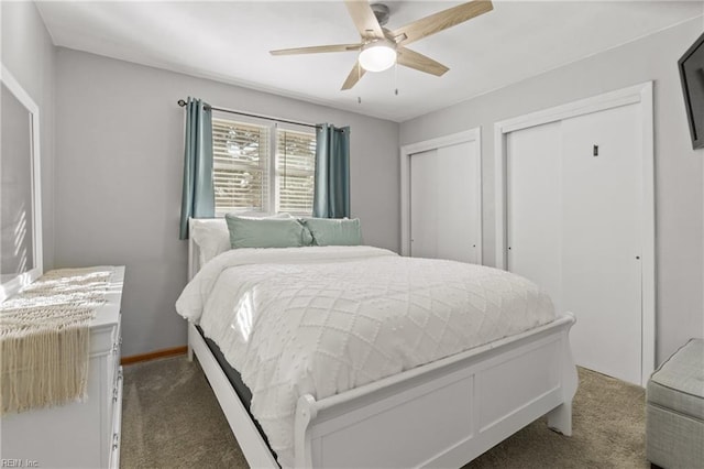 bedroom featuring baseboards, dark carpet, ceiling fan, and multiple closets