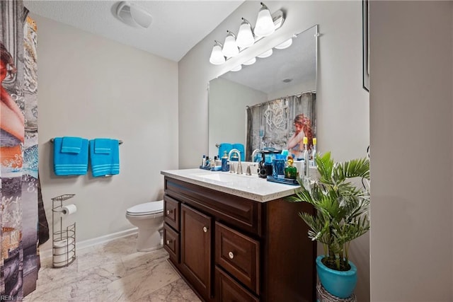 bathroom featuring marble finish floor, baseboards, vanity, and toilet