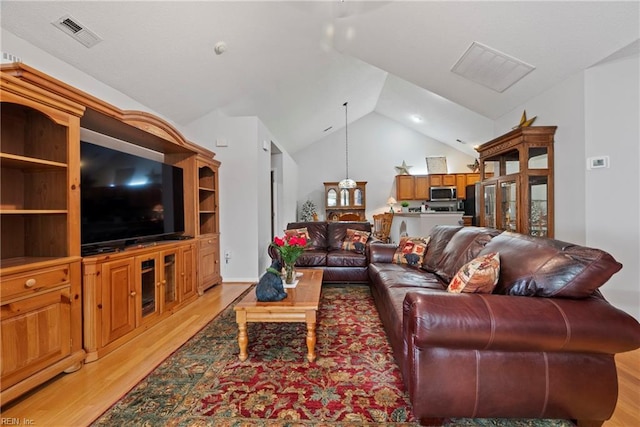 living room with high vaulted ceiling, visible vents, and light wood finished floors