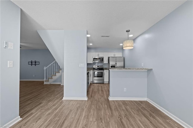 kitchen featuring pendant lighting, visible vents, appliances with stainless steel finishes, light wood-style floors, and white cabinets