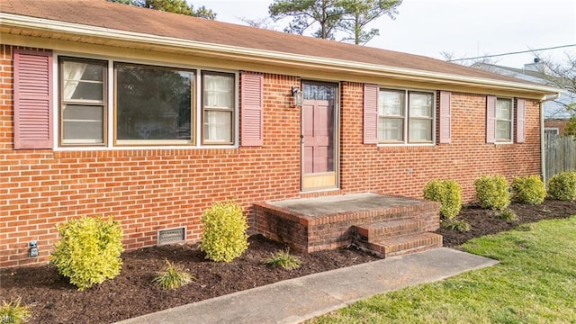 entrance to property featuring crawl space and brick siding