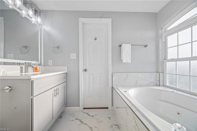 bathroom featuring marble finish floor, a garden tub, vanity, and baseboards