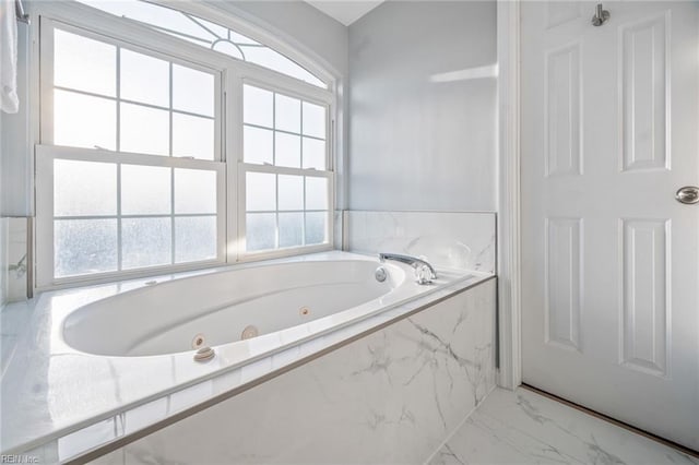 full bath featuring marble finish floor and a jetted tub