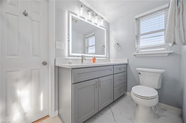 bathroom with toilet, marble finish floor, baseboards, and vanity