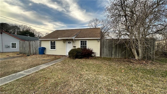 view of front of home featuring a front lawn, a shingled roof, fence, and an outdoor structure