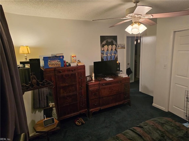 bedroom featuring a textured ceiling, dark carpet, and a ceiling fan