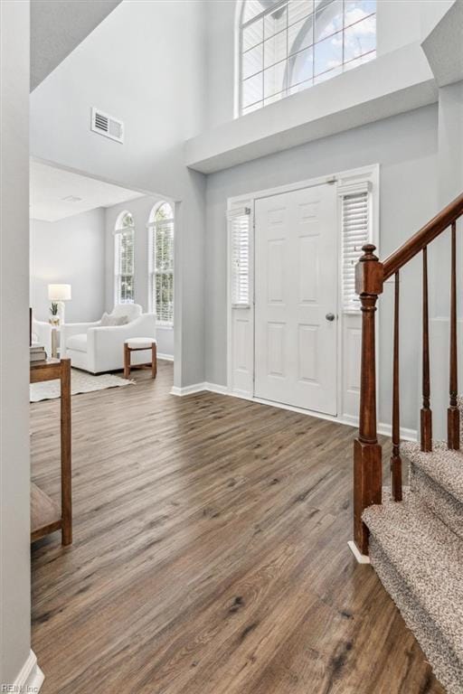 entrance foyer featuring stairs, a high ceiling, wood finished floors, and visible vents