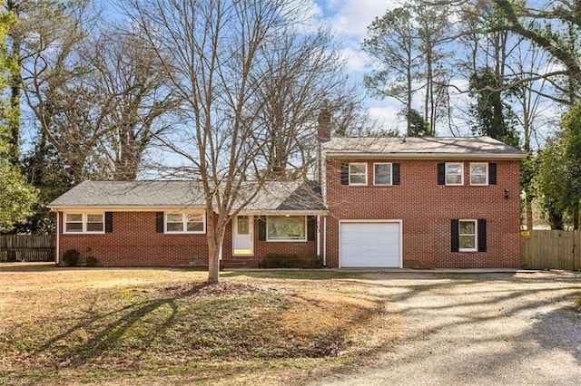 tri-level home featuring driveway, a chimney, an attached garage, fence, and brick siding