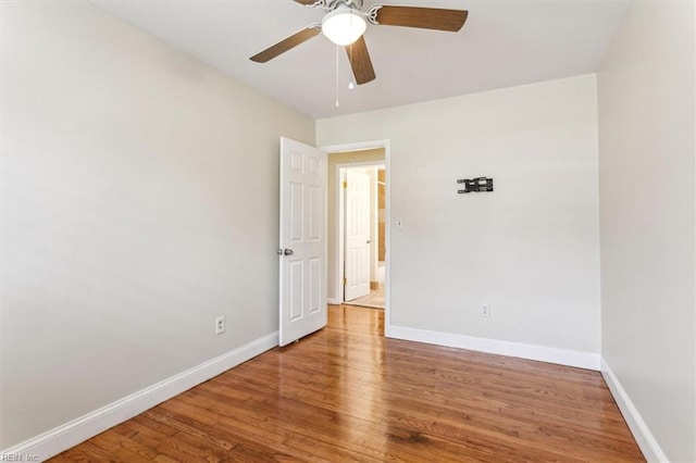 spare room with wood finished floors, a ceiling fan, and baseboards