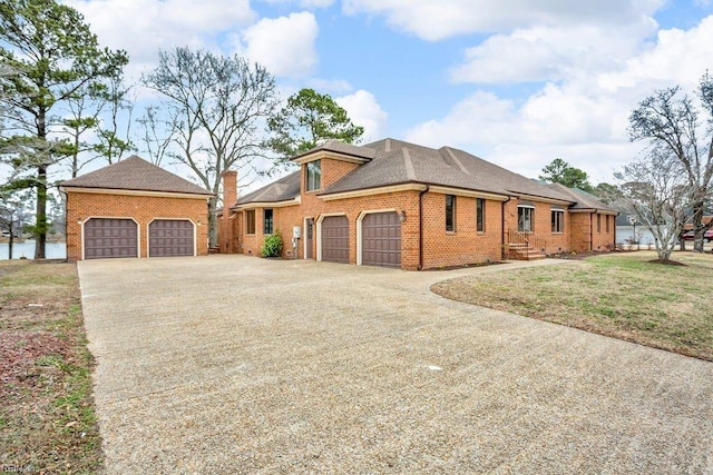 view of front of house featuring a garage, driveway, brick siding, and a chimney