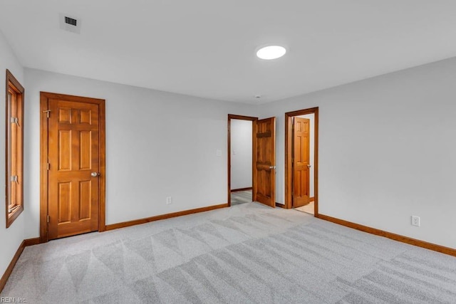 spare room featuring visible vents, light colored carpet, and baseboards