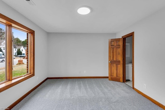 spare room featuring light carpet, visible vents, and baseboards