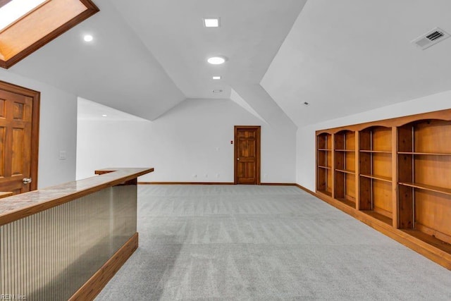 additional living space featuring light carpet, baseboards, visible vents, lofted ceiling with skylight, and recessed lighting