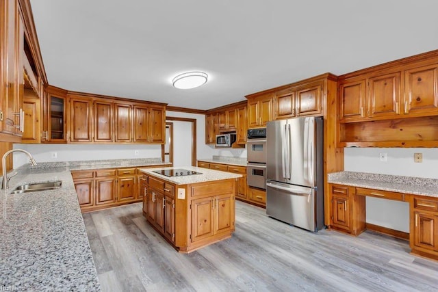 kitchen featuring stainless steel appliances, a kitchen island, a sink, built in study area, and brown cabinetry