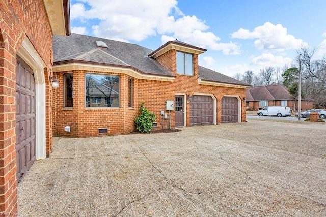 view of side of home featuring brick siding, a shingled roof, concrete driveway, an attached garage, and crawl space