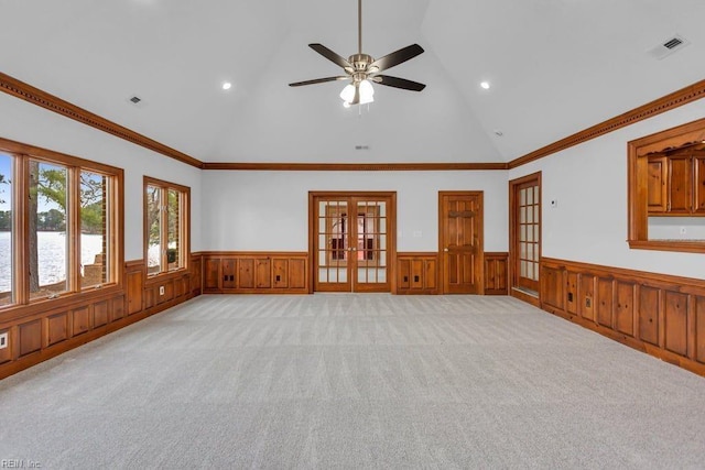 unfurnished room with lofted ceiling, a wainscoted wall, and french doors