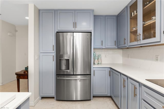 kitchen with glass insert cabinets, marble finish floor, light countertops, and stainless steel refrigerator with ice dispenser