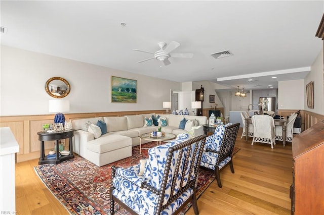 living room with a wainscoted wall, visible vents, and wood finished floors