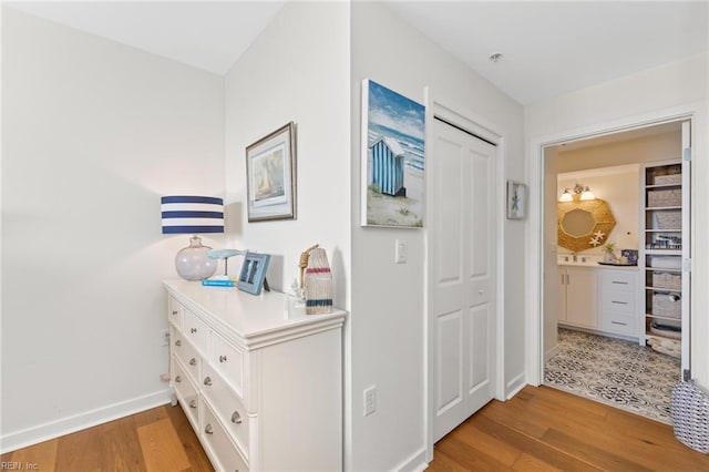 hall with light wood-style floors and baseboards