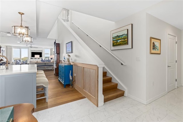 stairs with marble finish floor, a notable chandelier, and baseboards