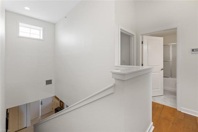 hallway featuring an upstairs landing, visible vents, wood finished floors, and recessed lighting