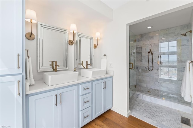 bathroom with wood finished floors, a sink, visible vents, and a shower stall