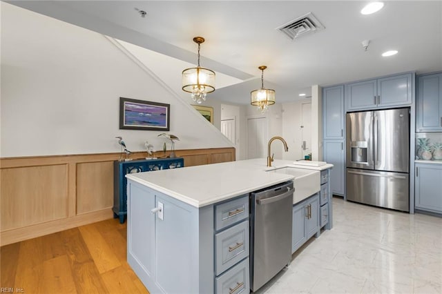 kitchen with a kitchen island with sink, stainless steel appliances, visible vents, light countertops, and pendant lighting