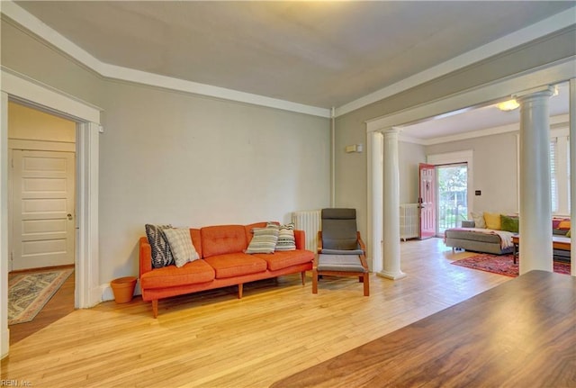 sitting room with ornamental molding, light wood-type flooring, and decorative columns