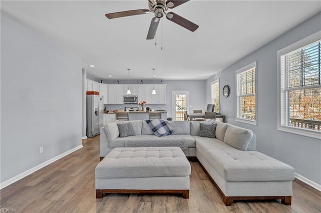 living area with baseboards, recessed lighting, a wealth of natural light, and light wood-style floors