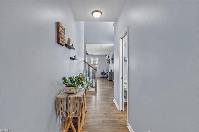 hall with light wood finished floors, stairway, and baseboards