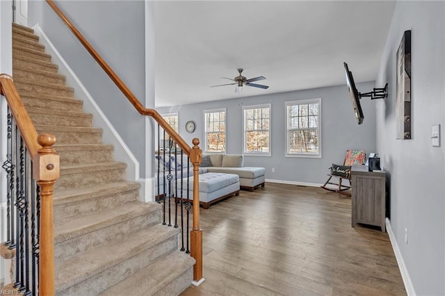 interior space with ceiling fan, stairway, baseboards, and wood finished floors