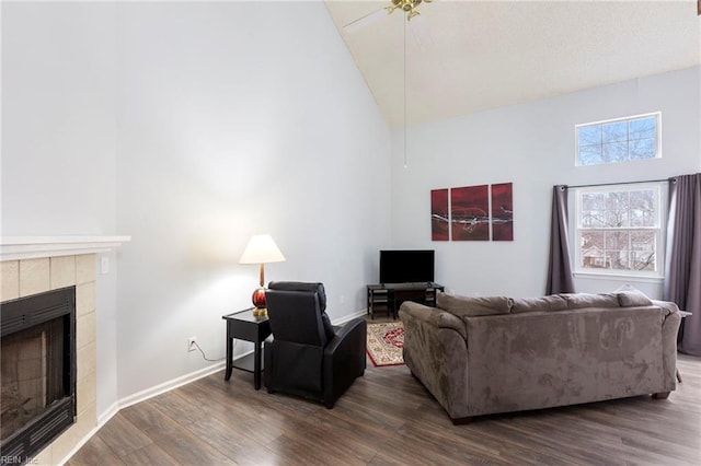 living area featuring high vaulted ceiling, baseboards, dark wood finished floors, and a tiled fireplace