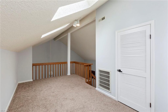 additional living space featuring lofted ceiling with skylight, carpet, visible vents, and a textured ceiling